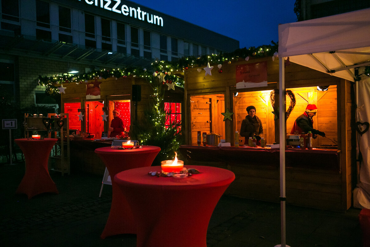 Stimmungsvolle Weihnachtsmarkt-Atmosphäre mit Buden und Stehtischen